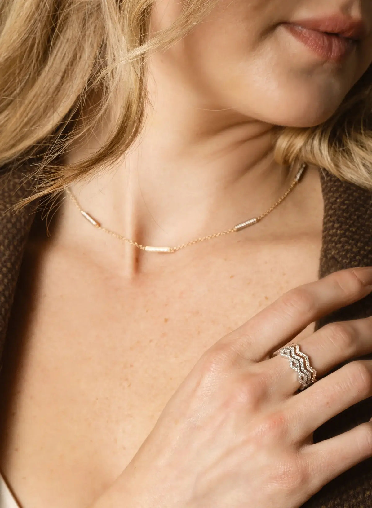 Close-up of a woman wearing Carin Susann layered necklaces and rings